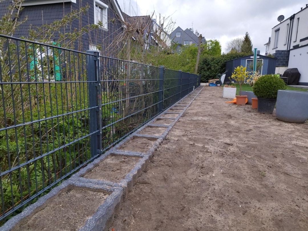 Neu gesetzter Doppelstabmattenzaun mit Betonfundamenten während der Montage