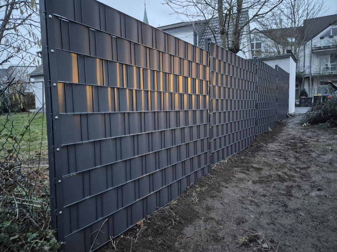 Frisch montierter Sichtschutzzaun mit eingeflochtenen Sichtschutzstreifen an einer Baustelle