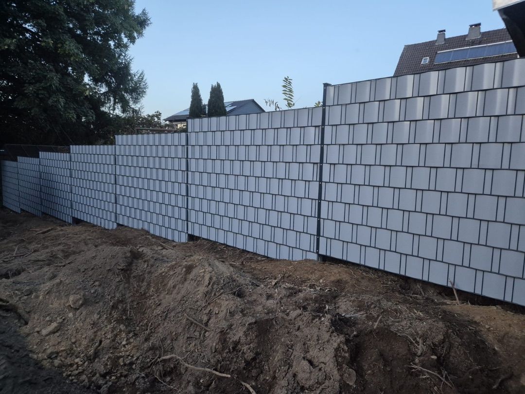 Sichtschutzzaun mit hellgrauen Sichtschutzstreifen an einem Grundstück im Bau