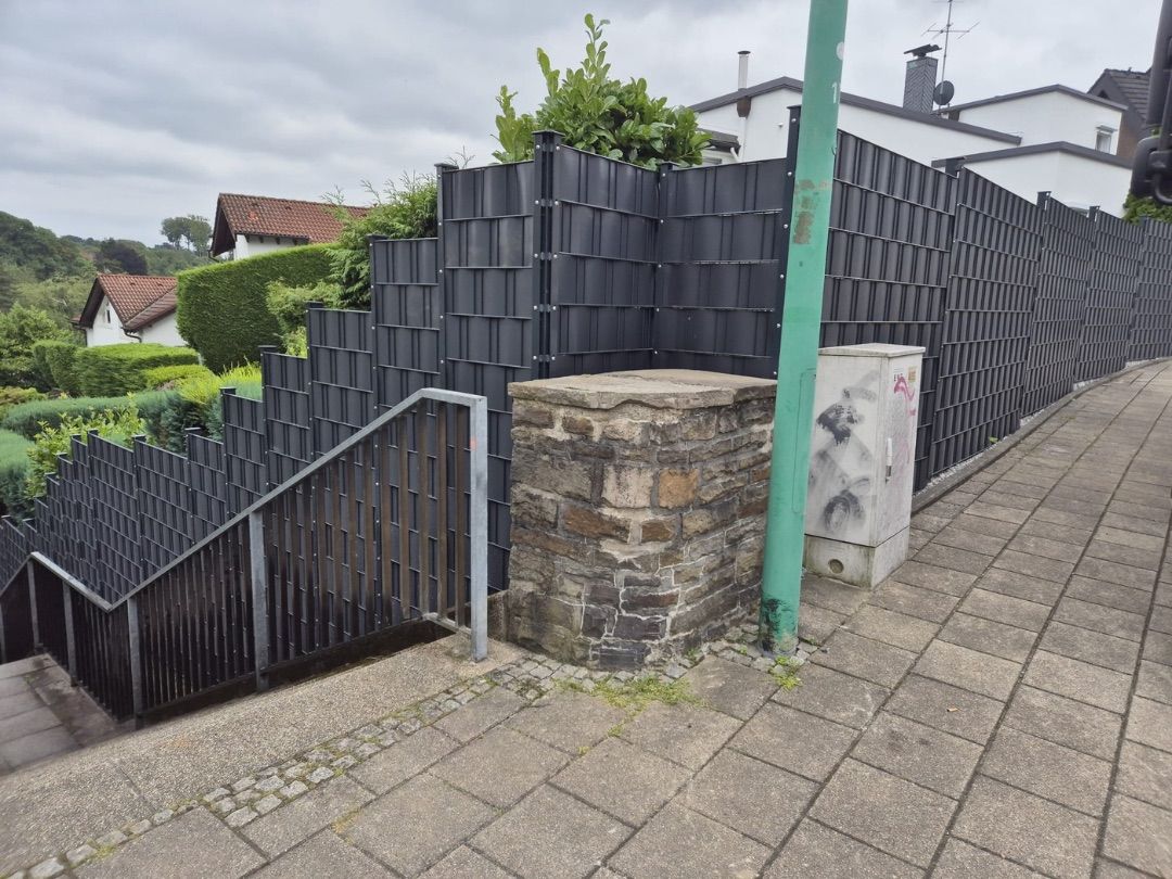 Sichtschutzzaun mit gemauertem Natursteinpfeiler und Gartentor am Grundstückseingang